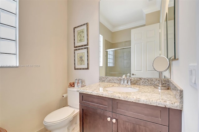 bathroom with crown molding, vanity, a shower with shower door, and toilet