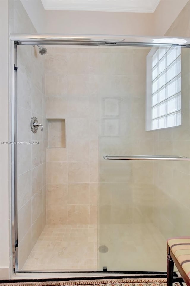 bathroom with a shower with shower door and crown molding