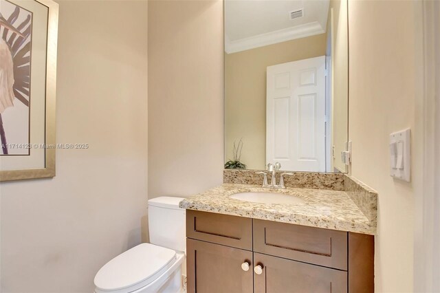 bathroom with vanity, toilet, and crown molding