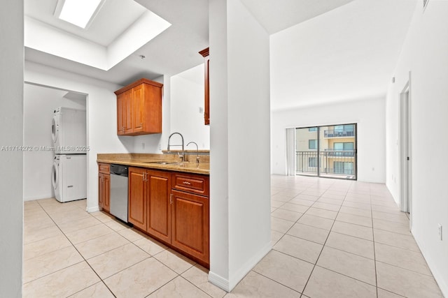 kitchen with light stone countertops, dishwasher, sink, stacked washer and dryer, and light tile patterned floors