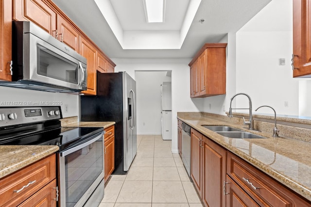 kitchen featuring light stone countertops, sink, light tile patterned floors, and stainless steel appliances