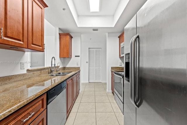 kitchen featuring a raised ceiling, sink, light stone countertops, appliances with stainless steel finishes, and light tile patterned flooring