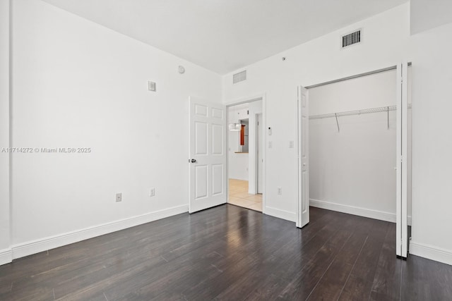 unfurnished bedroom featuring dark wood-type flooring and a closet