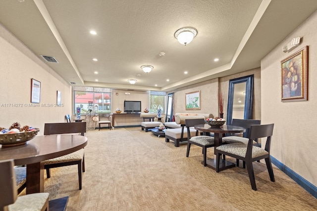 carpeted living room featuring a tray ceiling and a textured ceiling