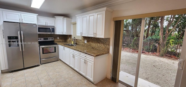 kitchen featuring appliances with stainless steel finishes, sink, dark stone countertops, and white cabinets