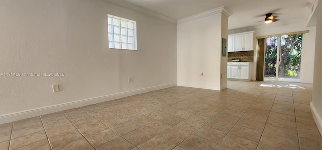 spare room featuring ceiling fan, ornamental molding, and light tile patterned floors