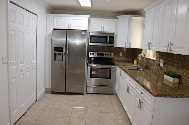 kitchen with sink, white cabinetry, dark stone countertops, stainless steel appliances, and decorative backsplash