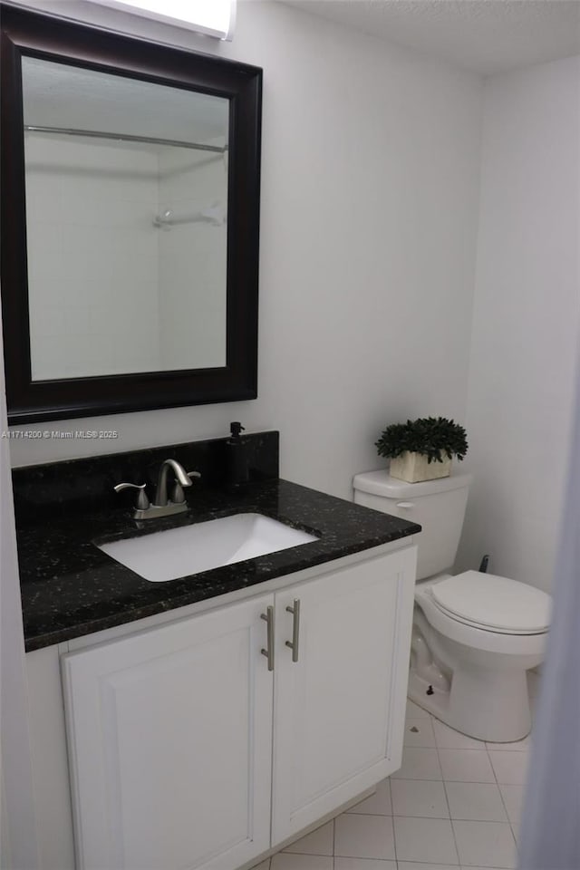 bathroom with tile patterned floors, vanity, toilet, and a textured ceiling