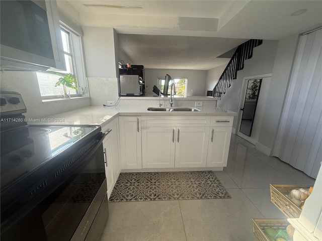 kitchen featuring white cabinets, sink, black range with electric cooktop, light tile patterned flooring, and kitchen peninsula