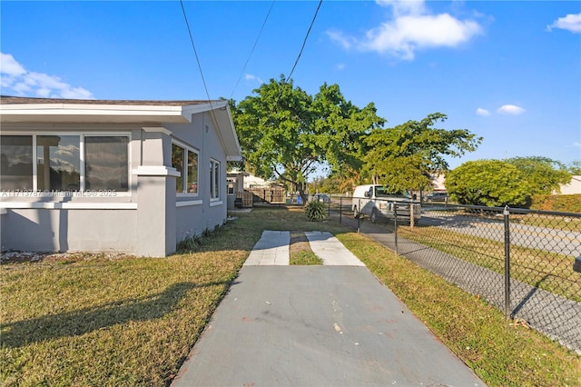 view of property exterior with fence, a lawn, and stucco siding