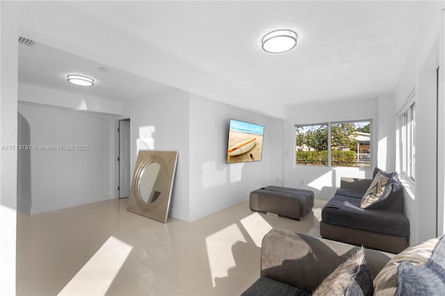 living room with a textured ceiling, visible vents, and baseboards