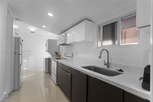 kitchen with white cabinets, electric stove, freestanding refrigerator, light countertops, and a sink