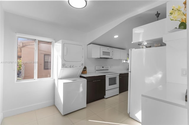 kitchen featuring light tile patterned floors, light countertops, stacked washer / dryer, white cabinets, and white appliances