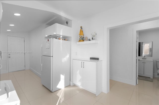 kitchen featuring freestanding refrigerator, a sink, recessed lighting, and light tile patterned floors