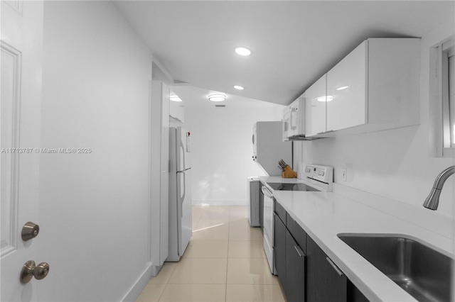 kitchen with light tile patterned floors, white appliances, a sink, white cabinetry, and light countertops