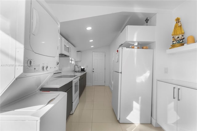 kitchen featuring stacked washer and clothes dryer, light countertops, light tile patterned flooring, white cabinetry, and white appliances