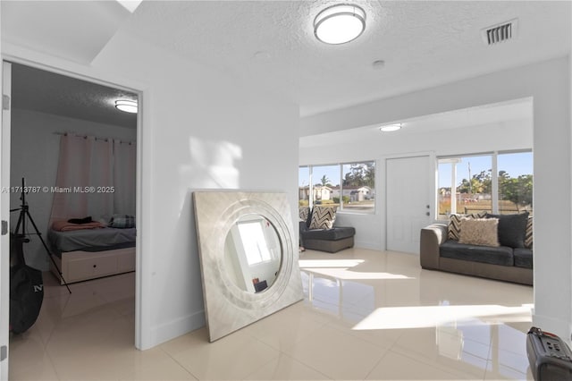 bathroom with a textured ceiling, connected bathroom, visible vents, and baseboards