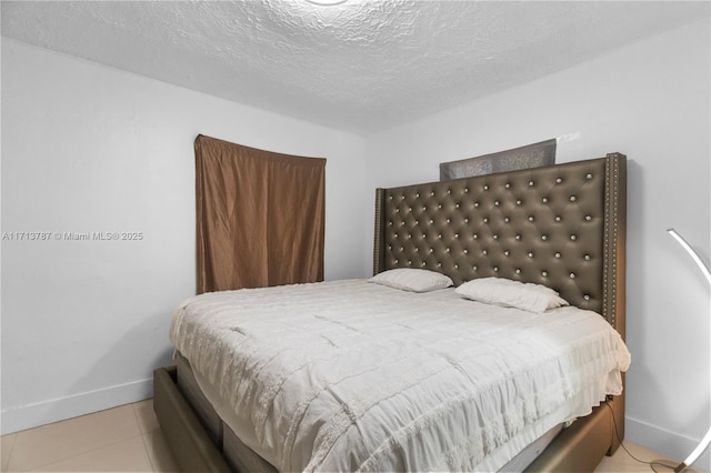 bedroom featuring baseboards, a textured ceiling, and tile patterned floors