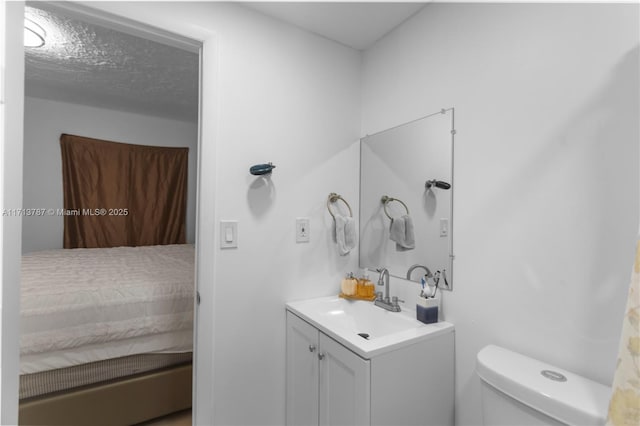 bathroom featuring connected bathroom, vanity, toilet, and a textured ceiling