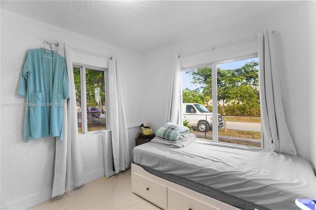 bedroom featuring multiple windows, a textured ceiling, and a textured wall