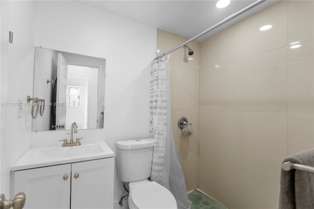 bathroom featuring tiled shower, vanity, and toilet