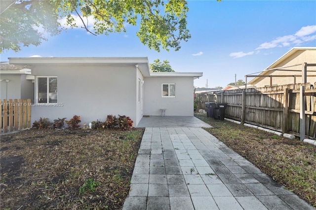 view of side of home featuring a patio area, fence, and stucco siding