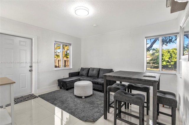 living area with a textured ceiling, baseboards, and tile patterned floors