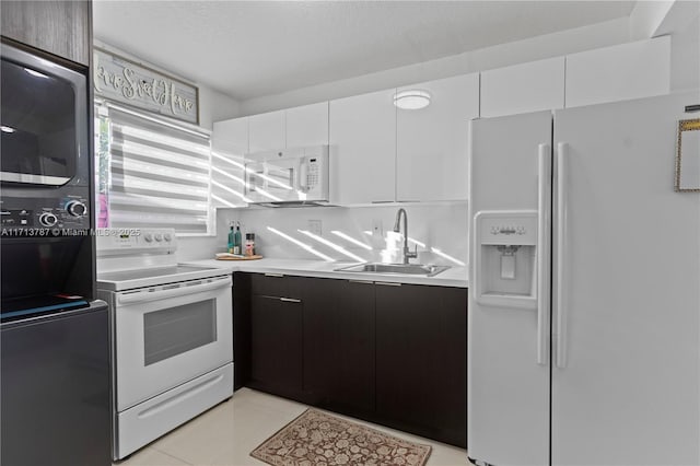 kitchen featuring white appliances, white cabinetry, light countertops, and a sink