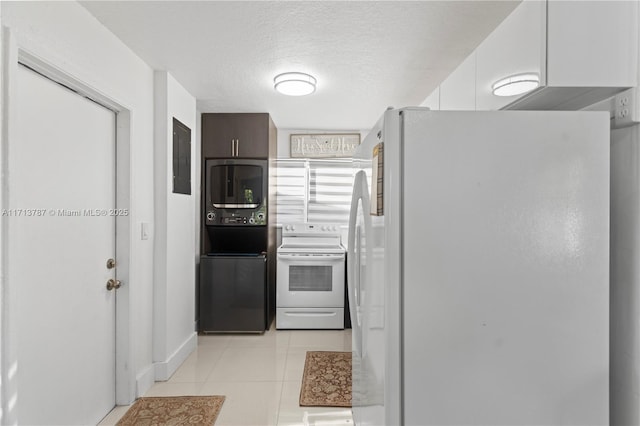 kitchen with stacked washer and dryer, white appliances, a textured ceiling, and light tile patterned floors