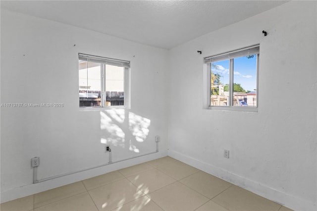 spare room with light tile patterned floors and baseboards