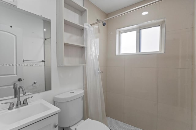 full bathroom featuring vanity, a tile shower, and toilet