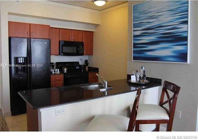 kitchen with black appliances, crown molding, kitchen peninsula, and sink