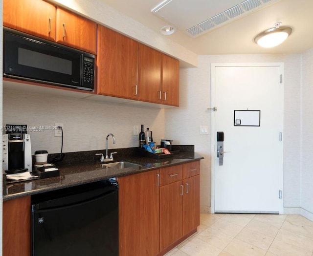 kitchen with dark stone countertops, sink, light tile patterned floors, and black appliances