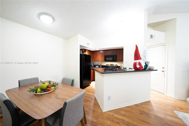 dining area featuring light hardwood / wood-style floors, a textured ceiling, and vaulted ceiling