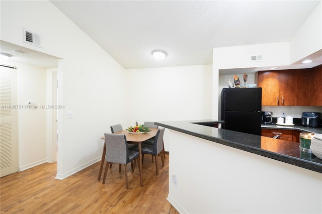 kitchen featuring black fridge, light wood-type flooring, and a textured ceiling