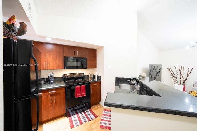 kitchen with kitchen peninsula, sink, black appliances, and light hardwood / wood-style floors