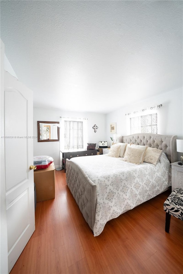 bedroom with hardwood / wood-style floors and multiple windows