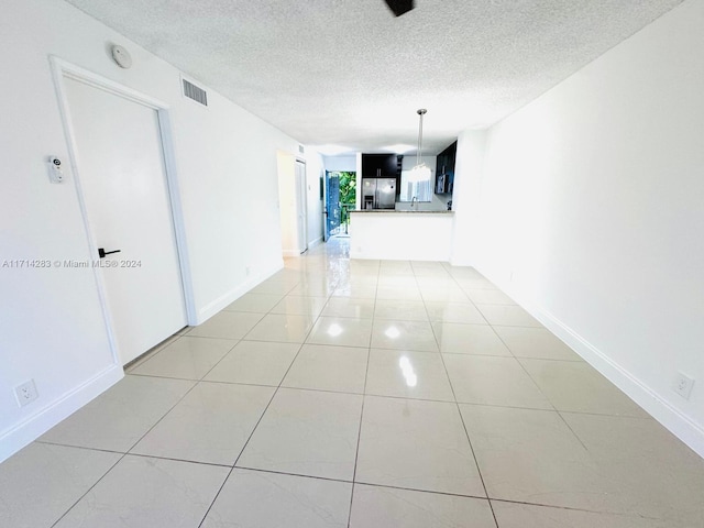 hall featuring light tile patterned flooring and a textured ceiling