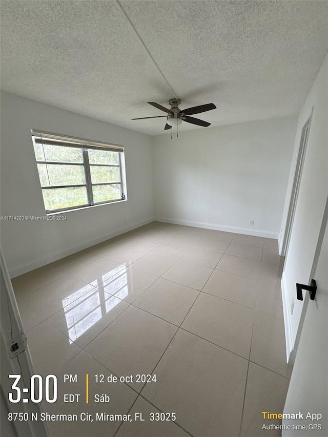 spare room featuring ceiling fan, light tile patterned floors, and a textured ceiling