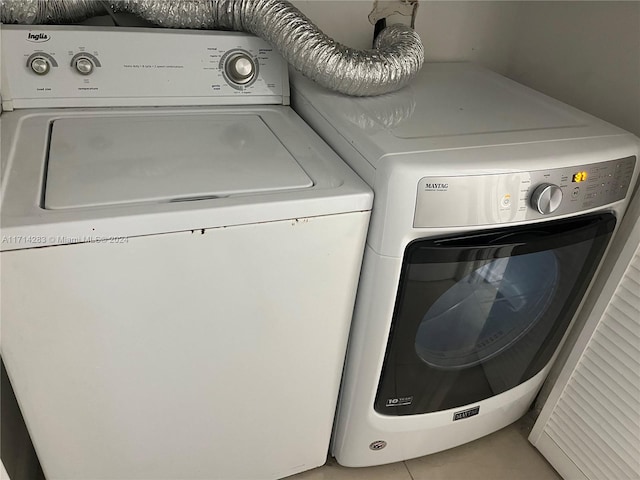 laundry area with washing machine and clothes dryer and light tile patterned flooring