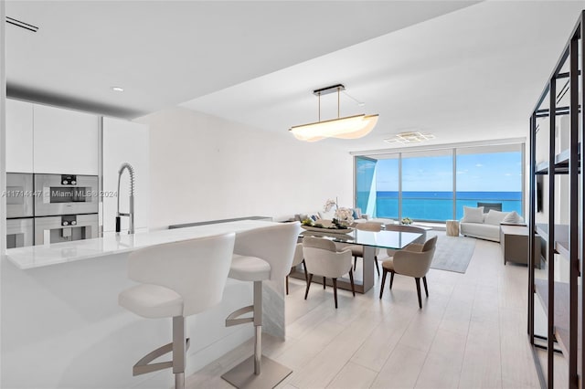 dining room featuring expansive windows, sink, and a water view