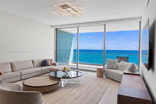 living room with floor to ceiling windows, a water view, and hardwood / wood-style flooring