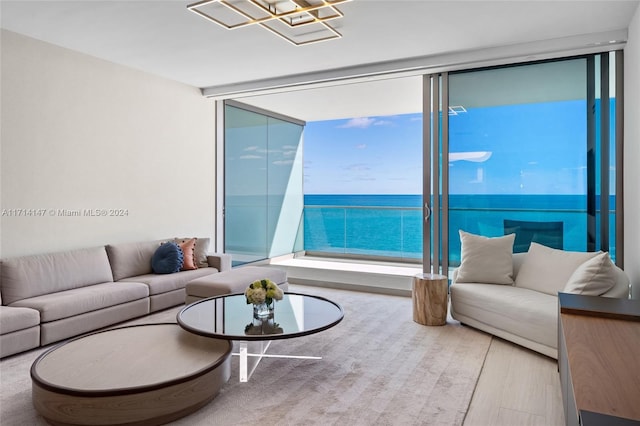 living room featuring light wood-type flooring, a water view, and a wall of windows