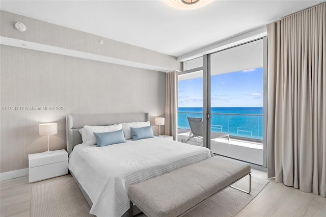 bedroom with access to outside, a water view, and a wall of windows