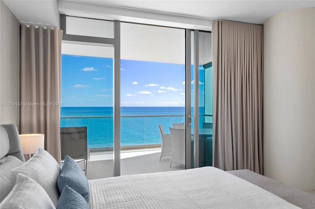 bedroom featuring access to outside, a water view, and expansive windows