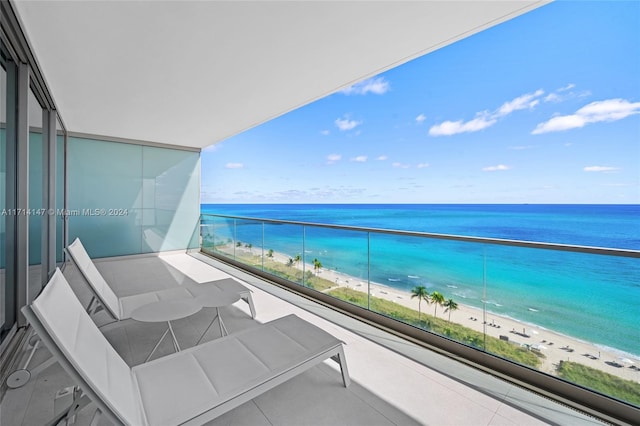 balcony featuring a view of the beach and a water view