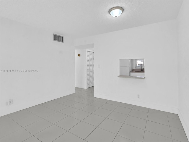 empty room featuring light tile patterned flooring and a textured ceiling