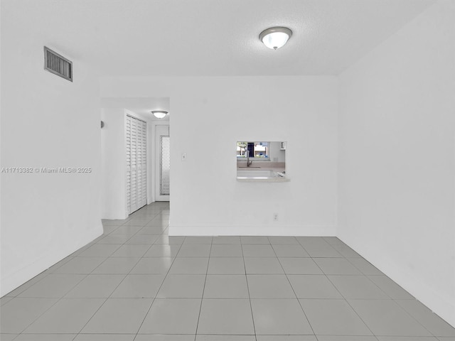 tiled spare room featuring a textured ceiling