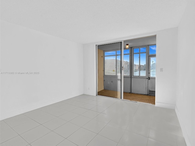 tiled spare room featuring a water view and a textured ceiling