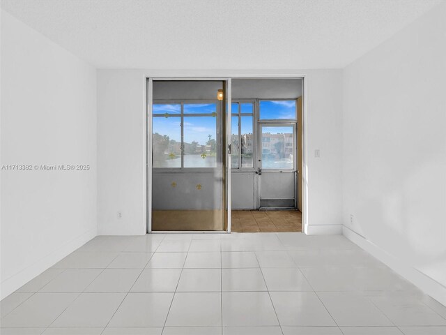 tiled spare room featuring a water view and a textured ceiling